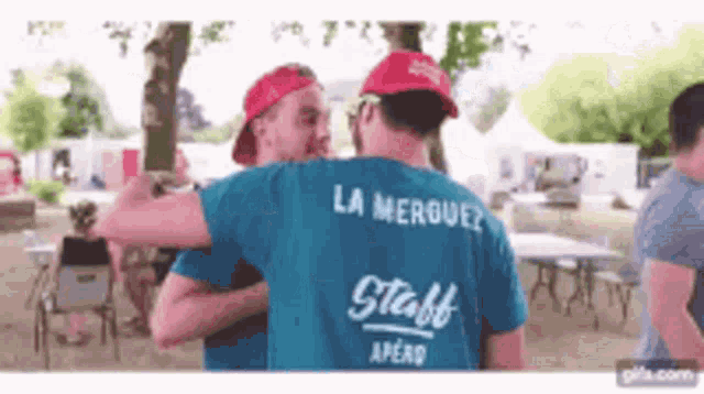 a man wearing a blue staff shirt is hugging another man