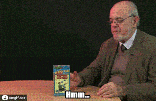an older man is sitting at a table holding a box that says " hmm "