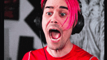 a man with pink hair is wearing headphones with his mouth open