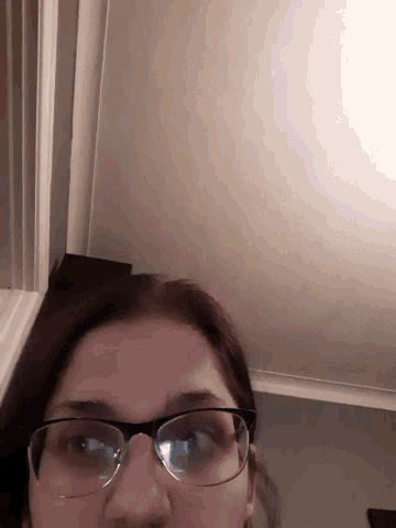 a woman wearing glasses looks down at something