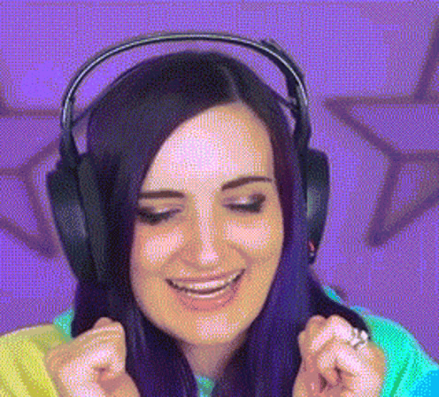 a woman with purple hair wearing headphones and a ring on her finger