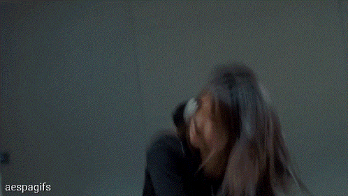 a woman in a black crop top is standing in front of a mirror with her hands on her head .