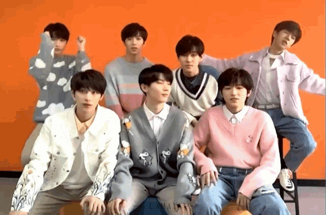 a group of young men are posing for a picture in front of an orange background .