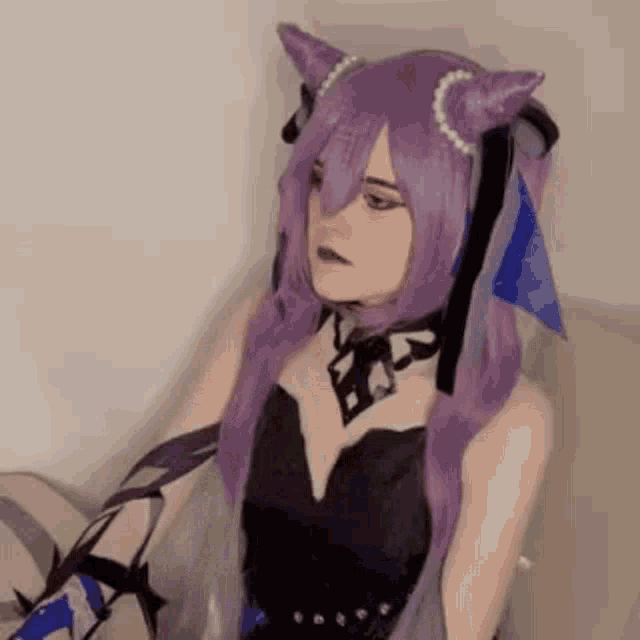 a woman with purple hair and cat ears is wearing a black dress and a purple wig .