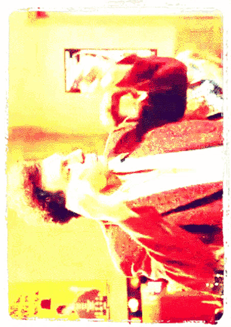a man in a red shirt is laying on his back in a room