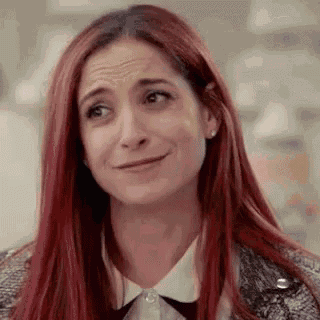 a woman with red hair is making a funny face and looking at the camera .