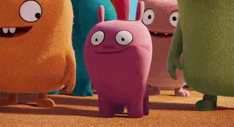 a group of stuffed monsters including a pink one with big eyes