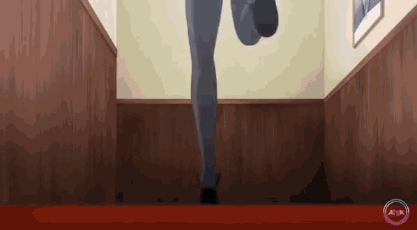 a woman is walking down a hallway with a red carpet .