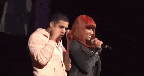 a man and a woman are singing into microphones on stage .