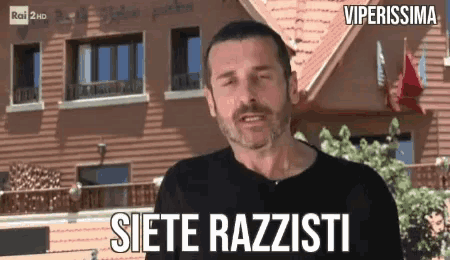 a man stands in front of a building with the words siete razzisti on the bottom
