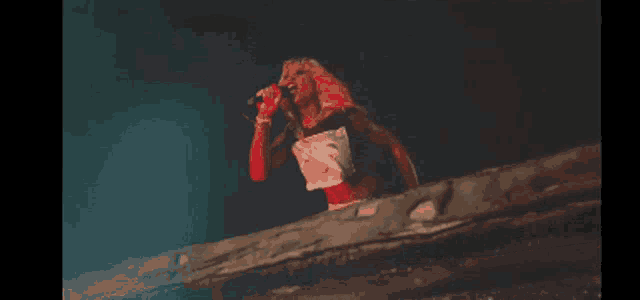 a woman singing into a microphone while wearing a shirt that says ' s ' on it