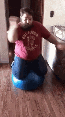 a man wearing a red shirt that says gryffindor is jumping on a blue ball