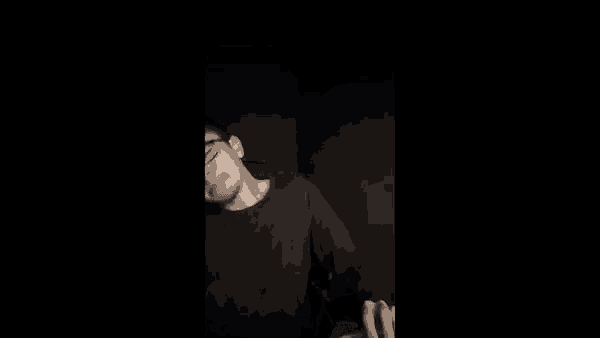 a man with glasses is pointing at the camera with his fist .