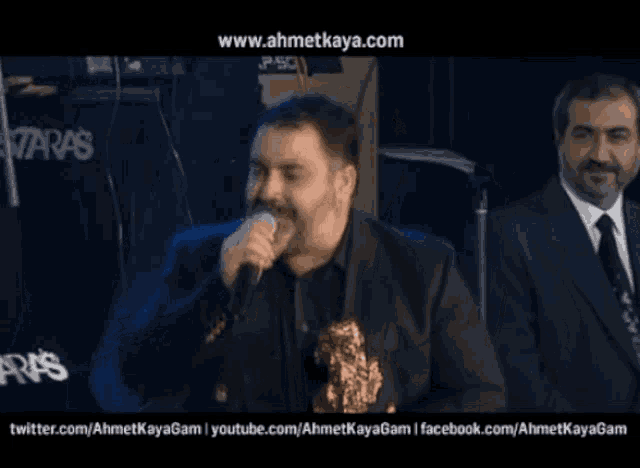 a man singing into a microphone with the website www.ahmetkaya.com visible