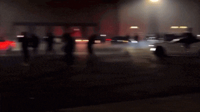 a car is driving down a street at night with smoke coming out of it