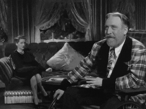 a man in a plaid shirt is smoking a cigar while a woman sits on a couch