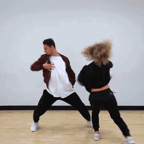 a man and a woman are dancing on a wooden floor .