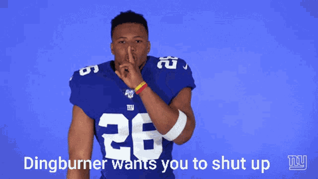 a man in a ny giants jersey holds his finger to his lips