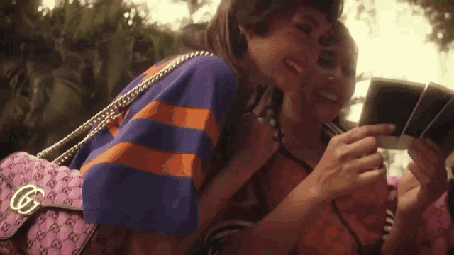 a woman is taking a picture of another woman with a pink purse
