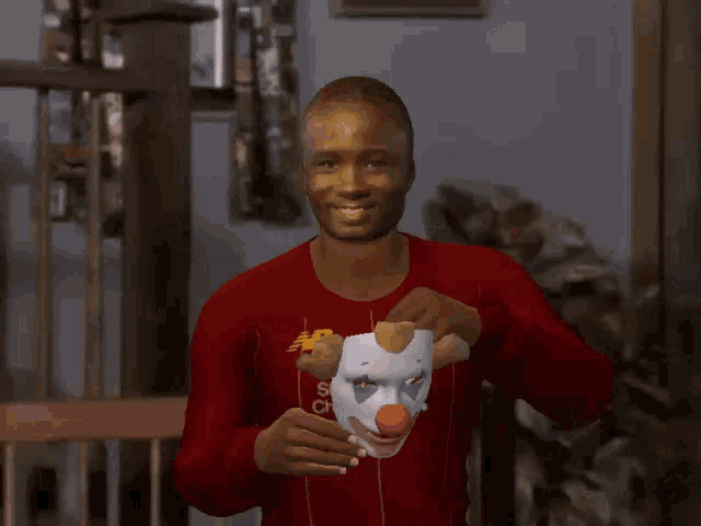 a man wearing a clown mask is wearing a red shirt that says standard chartered