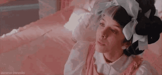 a woman is sitting on a bed wearing a pink dress and a white shirt .
