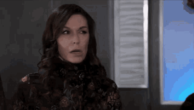 a woman is making a funny face while standing in front of a window in a room .