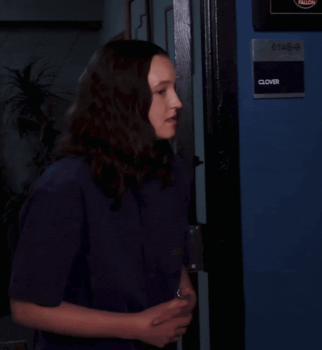 a woman stands in front of a blue door that says clovers