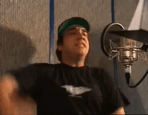 a man is standing in front of a microphone in a recording studio .