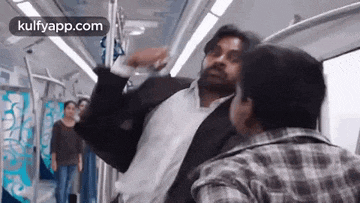 a man in a suit is fighting another man in a plaid shirt on a train .