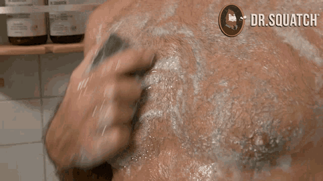 a shirtless man is taking a shower with dr. squatch written on the corner