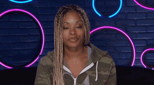 a woman with braids is wearing a green camo sweatshirt with the letter a on it