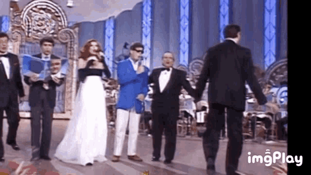a group of people are standing on a stage holding hands and singing into microphones .