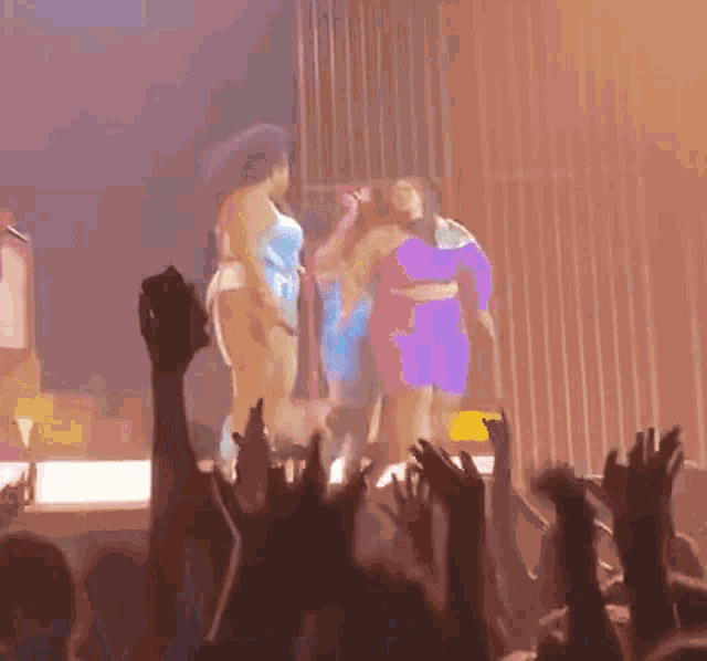 a group of women standing on a stage with their arms in the air