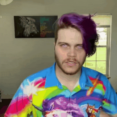 a man with purple hair is wearing a colorful shirt with unicorns on it