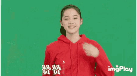 a woman in a red hoodie is smiling and waving her hands .