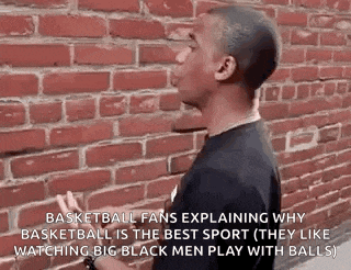 a man is standing in front of a brick wall and talking about basketball .