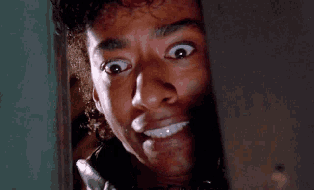 a man with a surprised look on his face looks through a door