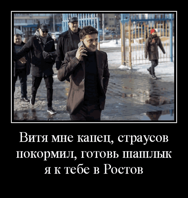 a man in a suit is talking on a cell phone while walking down a street