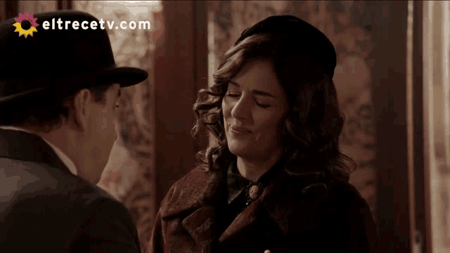 a man and a woman are looking at each other with eltrecetv.com in the background