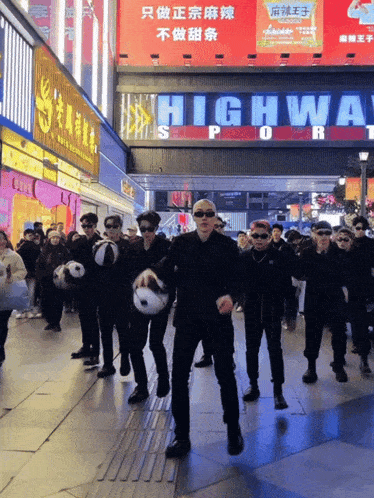 a group of people are dancing in front of a highway sign