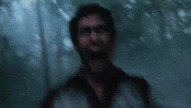 a close up of a man 's face with his mouth open and trees in the background