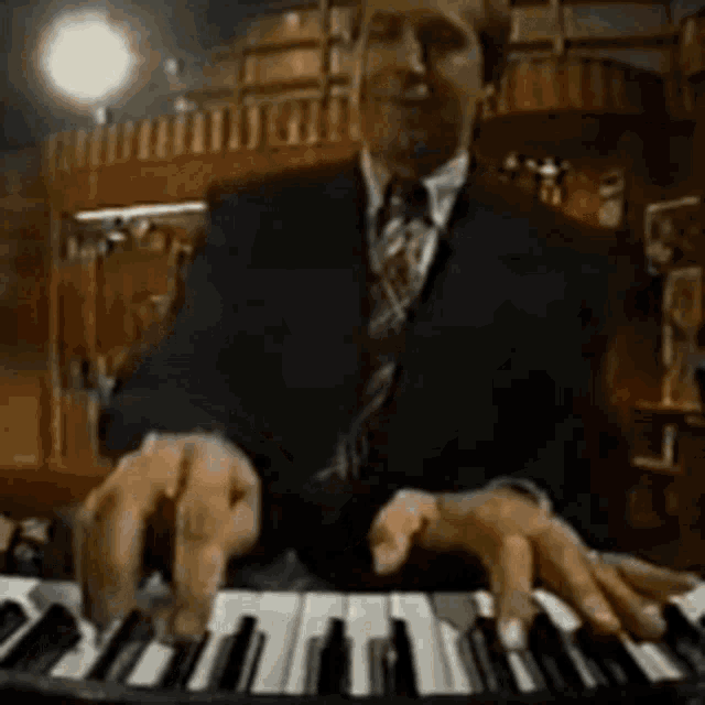 a man in a suit is playing a piano