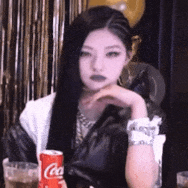 a woman sits at a table with a coca cola can in front of her