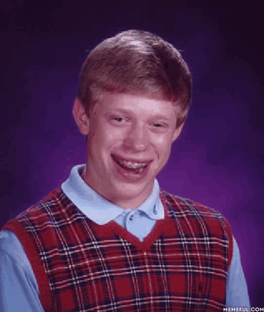a man wearing a plaid vest and a blue shirt is smiling