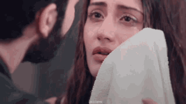 a woman is crying and covering her face with a white towel .