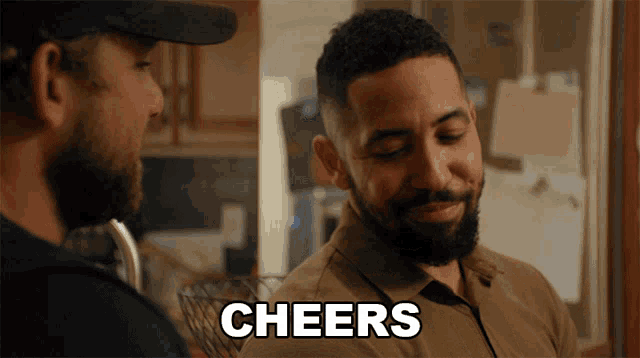 a man with a beard talks to another man with the word cheers written on the screen