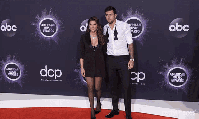 a man and a woman pose on the red carpet for the american music awards on abc