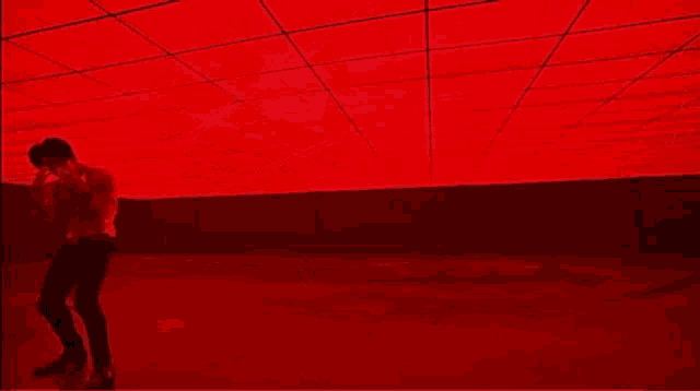 a man is standing in a dark room with his arms outstretched in front of a red ceiling .