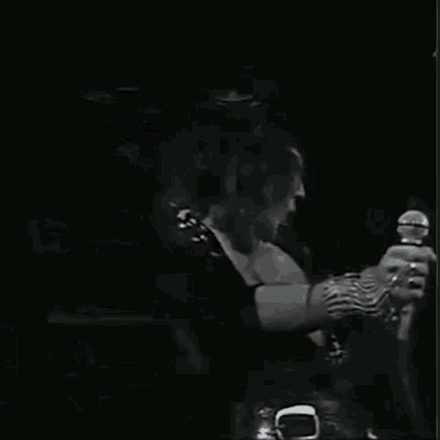 a man is playing a guitar on a stage in a dark room .