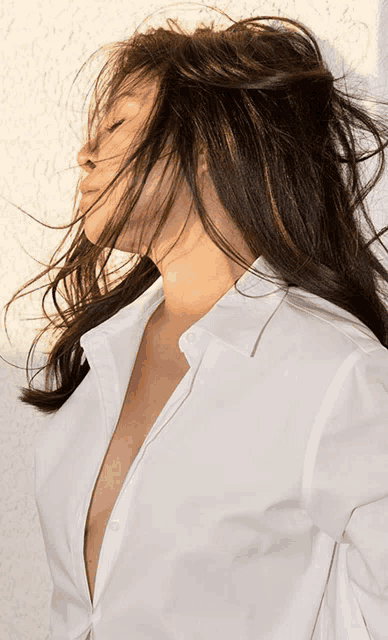 a woman wearing a white shirt has her eyes closed